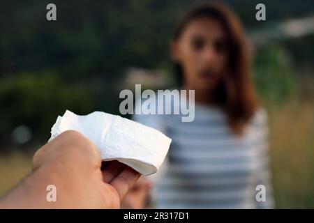 Ich biete einer erkälteten Frau ein Taschentuch an. Stockfoto