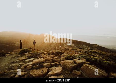 Zwei Männer stehen auf dem Berg und beobachten den Sonnenaufgang Stockfoto
