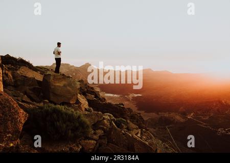 Ein Mann steht auf dem Gipfel des Berges und sieht den Sonnenuntergang Stockfoto