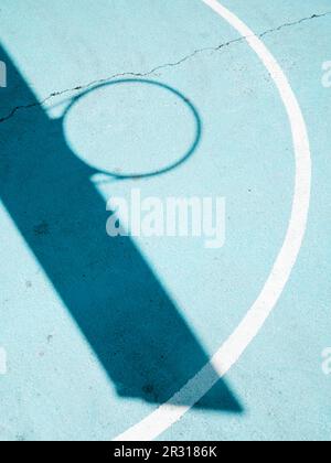 Schatten eines Basketballkörpers auf blauem Platz Stockfoto