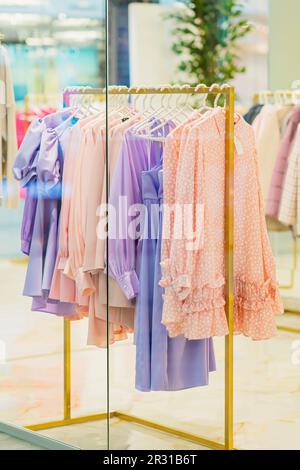 Sommerkleidung für Damen, die an der Schiene hängt. Verschwommener Blick durch das Schaufenster, weicher Fokus Stockfoto