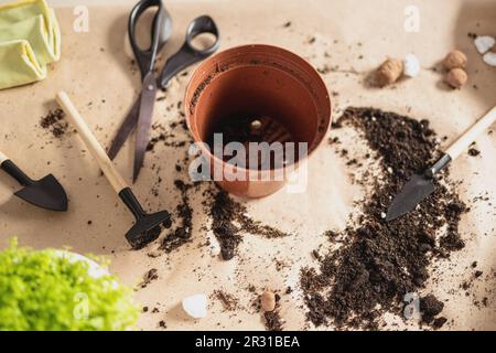 Leere Töpfe, Erde, Gartengeräte auf Kunsthandwerkstoff-Hintergrund Stockfoto