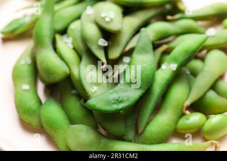 Grüne Edamame-Bohnen in Hülsen mit Salz auf dem Teller, Nahaufnahme Stockfoto