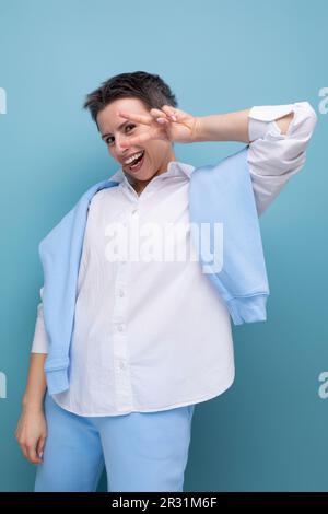 Vertikales Foto einer stilvollen, modischen jungen Dame mit Hülsenhaar in einem weißen Hemd in ungezwungener Atmosphäre Stockfoto