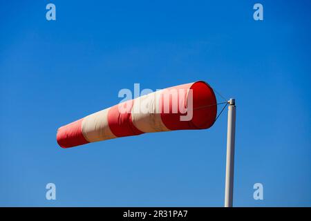 Rot-weiße Windsocken mit hoher Windstärke und klarem blauem Himmel. Stockfoto