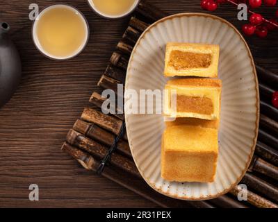 Köstliches taiwanesisches berühmtes Ananaskuchen Gebäck als Dessert auf einem Teller auf einem Holztisch mit heißem Tee. Stockfoto