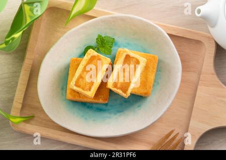 Köstliches taiwanesisches berühmtes Ananaskuchen Gebäck als Dessert auf einem Teller auf einem Holztisch mit heißem Tee. Stockfoto