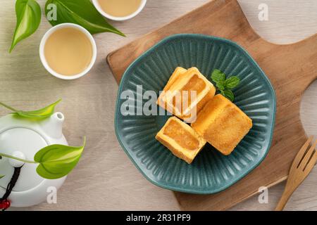 Köstliches taiwanesisches berühmtes Ananaskuchen Gebäck als Dessert auf einem Teller auf einem Holztisch mit heißem Tee. Stockfoto