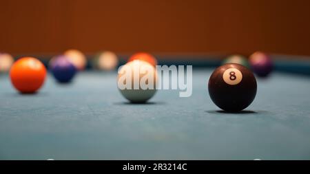 8 Ball und andere Billardbälle auf dem blauen Billardtisch Stockfoto