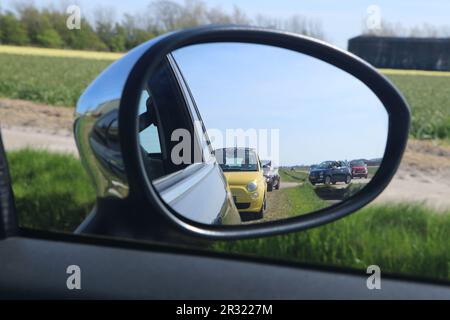 Der Seitenspiegel reflektiert mehrere Fiat 500-Fahrzeuge in holländischer Landschaft in Julianadorp, Niederlande - April 30 2023 Stockfoto