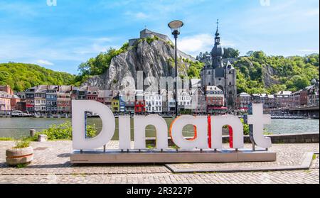 DINANT, BELGIEN - 18. Mai 2023: Stadtzentrum von Dinant mit großem Wortzeichen entlang der Maas. Zitadelle im Hintergrund. Stockfoto