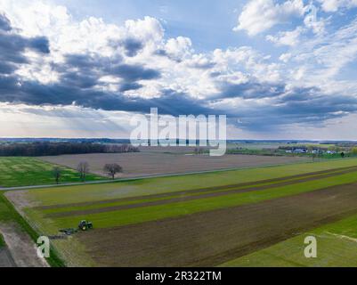 Fesselnde Landschaft: Traktor, der das Feld unter einem malerischen Himmel anpflückt. Stockfoto