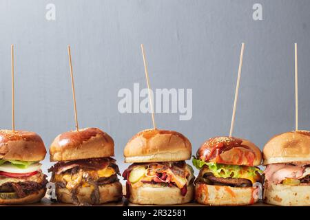 Viele verschiedene Burger mit Zutaten auf einer Holzplatte Stockfoto