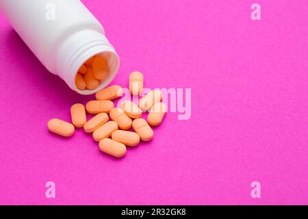 Weiße medizinische Tabletten und Pillen, die aus einer Arzneimittelflasche verschüttet wurden. Makroansicht von oben nach unten mit Kopierbereich. Stockfoto