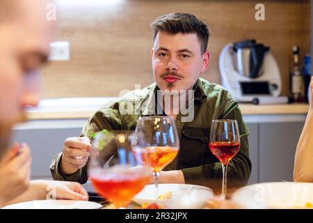 Nahaufnahme eines jungen Mannes zu Hause, der eine Weinprobe veranstaltet. Hochwertiges Foto. Stockfoto