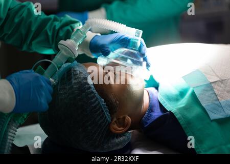 Mittelschnitt verschiedener Chirurgen und Patientin mit Sauerstoffmaske im Operationssaal Stockfoto