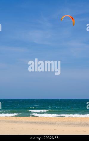 Ein männlicher Kitesurfer hat seinen Drachen geworfen und ist bereit, vom Strand in die Wellen in Mui Ne, Vietnam, zu fahren. Stockfoto