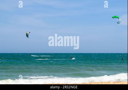 Zwei Kitesurfer in Aktion am Strand in Mui Ne, Vietnam. Stockfoto