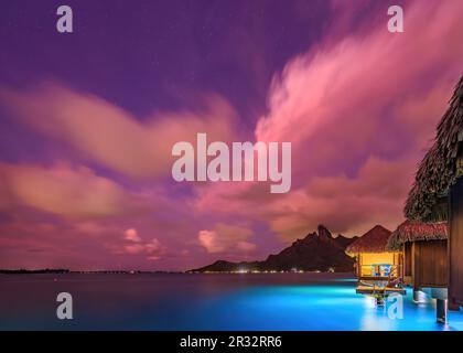 Wunderschöne Sonnenaufgangsfarbe der Überwasservilla am St. Regis Bora Bora Resort, mit dem Berg Otemanu Stockfoto