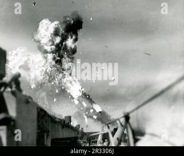 Die USS Intrepid wird von einem Kamikaze vor Luzon, Philippinen, getroffen, 25. November 1944. Das Flugzeug ist gerade explodiert und die explodierenden Trümmer regnen auf den Träger. Ein bemerkenswertes Foto, das zeigt, wie die USS Essex von einem Kamikaze östlich von Luzon, Philippinen, getroffen wird, 25. November 1944. Die Rauchspur aus dem Flugzeug ist noch immer in der Luft sichtbar, was zum Aufprall und zur Explosion führt. Als Japan Ende 1944 mit einer Niederlage konfrontiert war, entschied es sich, US-Schiffe mit Selbstmordattentaten, Kamikaze genannt, zu zerstören. Diese Angriffe waren eine starke physische und psychologische Waffe und versenkten insgesamt 47 Schiffe Stockfoto