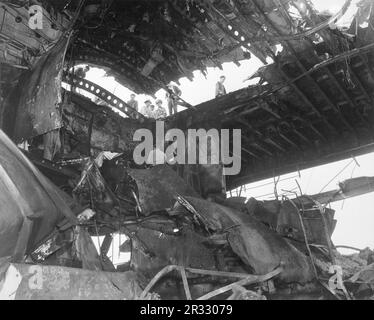 Seeleute, die den Schaden sehen, der dem Flugzeugträger USS Randolph durch einen japanischen Kamikaze-Angriff zugefügt wurde. Als Japan Ende 1944 mit einer Niederlage konfrontiert war, entschied es sich, US-Schiffe mit Selbstmordattentaten, bekannt als Kamikaze, zu zerstören. Diese Angriffe waren eine starke physische und psychologische Waffe und versenkten insgesamt 47 Schiffe zu einem Preis von mehr als 3000 Piloten und Flugzeugen. Ende 1944 war die US-Marine so groß, dass die Verluste unbedeutend waren und den Verlauf des Krieges nicht veränderten. Stockfoto