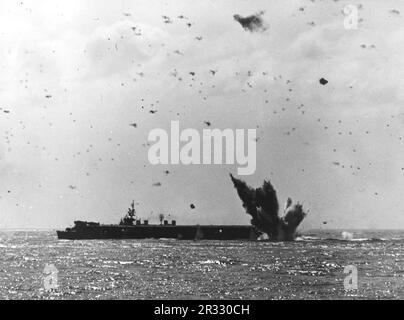 Ein japanisches Flugzeug stürzt in der Nähe des Hecks eines US-Flugzeugs ab Navy Light Aircraft Carrier, während eines erfolglosen Kamikaze-Angriffs am 17. April 1945. Da das Foto vom Schlachtschiff USS South Dakota (BB-57) aufgenommen wurde, ist der Träger höchstwahrscheinlich USS Bataan Stockfoto