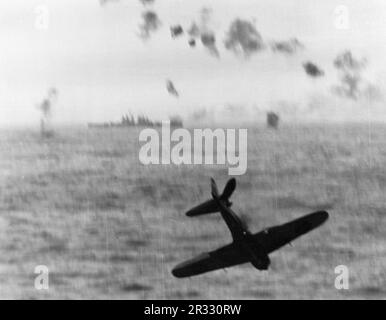 Japanischer Mitsubishi A6M5 Zero Kamikaze-Kämpfer, bevor er ins Meer stürzt, nachdem er versucht hatte, die USA zu treffen Navy Aircraft Carrier USS Essex (CV-9) vor Okinawa, 1945. Beachten Sie den leichten Cruiser der Cleveland-Klasse im Hintergrund. Stockfoto