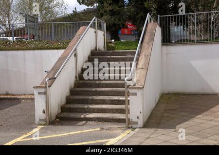 Eine Reihe von Betontreppen, die den Zugang zwischen Geschäften im Industriegebiet von Bridgend über eine sehr befahrene Straße ermöglichen. Stockfoto