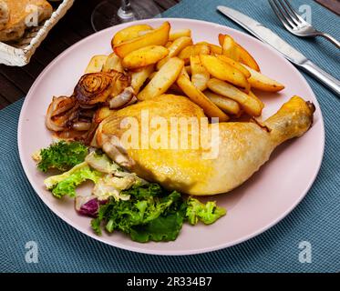 Hähnchenschenkel mit gebackenen Kartoffeln, braunen Zwiebeln und frischem Salat Stockfoto