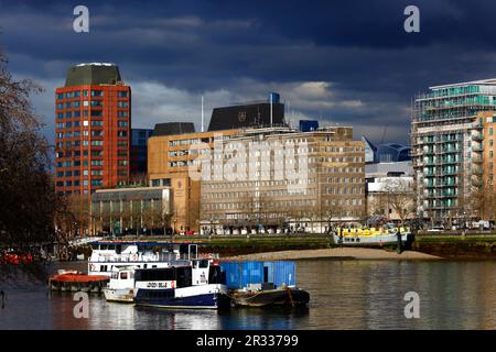 Themse, Westminster Tower (L) und Büros der Internationalen Seeschifffahrtsorganisation (Zentrum) unter stürmischem Himmel, London Belle Partyboot im Vordergrund Stockfoto