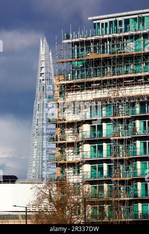 Leute sitzen auf dem Balkon eines neuen Apartmentgebäudes am Albert Embankment, The Shard Tower im Hintergrund unter stürmischem Himmel, London, Großbritannien Stockfoto