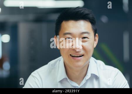Nahaufnahme eines jungen asiatischen Geschäftsmanns, Buchhalters, Geschäftsführers im Büro, der vor der Kamera lächelt. Stockfoto