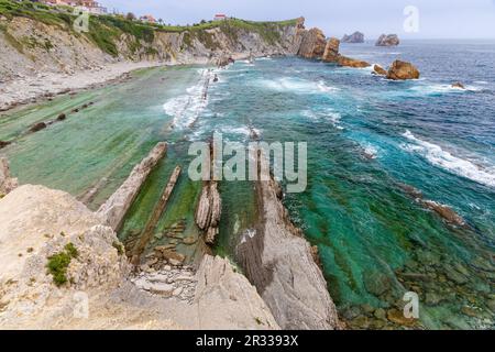 Atemberaubende Küstenformation mit majestätischen Felssäulen, die aus dem Meer aufsteigen und gegen die Wellen schlagen. Canales de los Urros, Arnia, Liencre Stockfoto