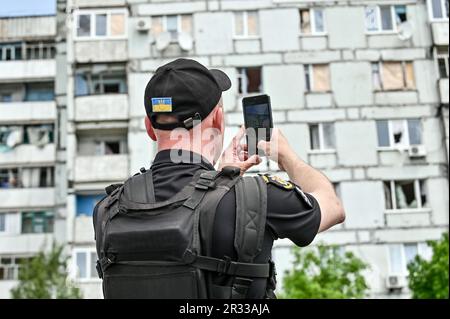 STEPNOHIRSK, UKRAINE - 19. MAI 2023 - Ein Polizeibeamter fotografiert ein Wohnhaus, das durch mehrere Granaten beschädigt wurde, die von russischem troo durchgeführt wurden Stockfoto