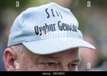 Berlin, Deutschland. 22. Mai 2023. Ein Mann trägt eine Mütze mit der Inschrift „Stop Uigur Genocide“ vor dem „Pillar of Sham“-Denkmal. Das Denkmal erinnert an die Opfer der gewaltsamen Unterdrückung der chinesischen Protestbewegung auf dem Tiananmen-Platz in Peking im Juni 1989. Kredit: Hannes P Albert/dpa/Alamy Live News Stockfoto