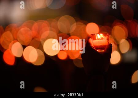 Menschen, die während der Verehrung des Heiligen Kreuzes nach der Heiligen Messe während des Mladifestes in Medjugorje Kerzen halten. Stockfoto