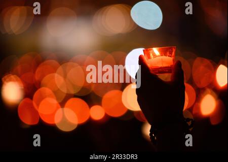 Menschen, die während der Verehrung des Heiligen Kreuzes nach der Heiligen Messe während des Mladifestes in Medjugorje Kerzen halten. Stockfoto