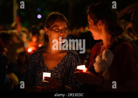 Menschen, die während der Verehrung des Heiligen Kreuzes nach der Heiligen Messe während des Mladifestes in Medjugorje Kerzen halten. Stockfoto