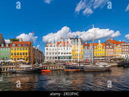 Kopenhagen, Dänemark - 13. September 2010: Berühmte Fassaden des Nyhavn Restaurants in hellen Farben entlang des mittleren Anlegebereichs unter blauer Wolkenlandschaft. Das Boot Stockfoto