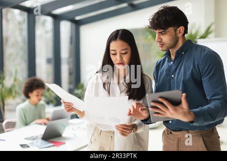 Asiatische Geschäftsfrau Und Arabischer Geschäftsmann, Die Tablet-Pcs Verwenden Und Im Büro Arbeiten Stockfoto