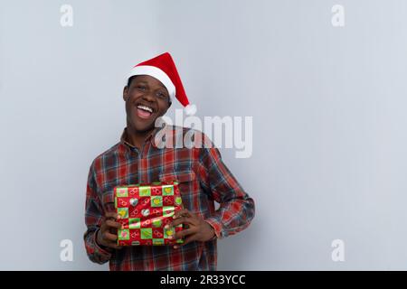 Afrikanischer Mann mit Weihnachtsmütze und Geschenken Stockfoto