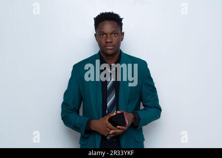 Porträt eines hübschen schwarzen afrikanischen Geschäftsmannes, der Anzug trägt und Smartphone hält Stockfoto
