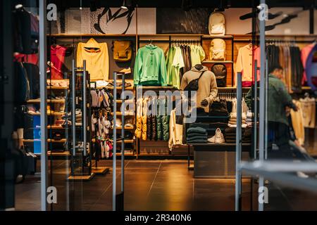 Dunkles Interieur des Sportgeschäfts im Einkaufszentrum, Kleidung und Schuhe, Accessoires für aktiven Lifestyle, abstrakter, verschwommener Hintergrund Stockfoto