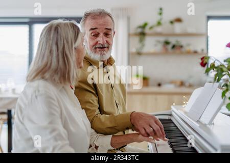 Wunderschönes älteres Paar, das zu Hause Klavier spielt Stockfoto