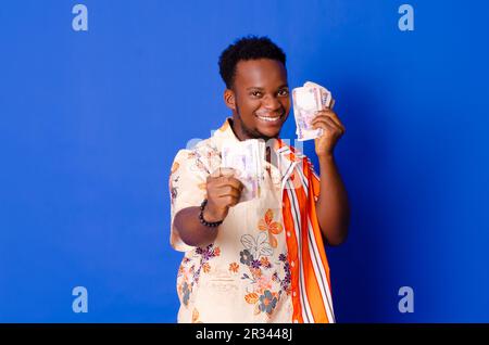 Ein afrikanischer Mann, der fröhlich und glücklich ist und viel Geld in der Hand hat. Stockfoto