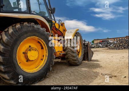 Details des modernen roten Traktors aus der Nahaufnahme. Großer, leuchtend gelber, leistungsstarker Industrietraktor mit schwerem Bagger, Planierschild. Stockfoto