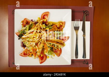 Ein Salat mit panierten gebratenen Hähnchenstreifen, Tomatenstückchen, Salat, Zuckermais und süßer Senf Vinaigrette Stockfoto