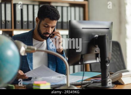 Junger Mann, der im Büro sitzt und arbeitet. Stockfoto