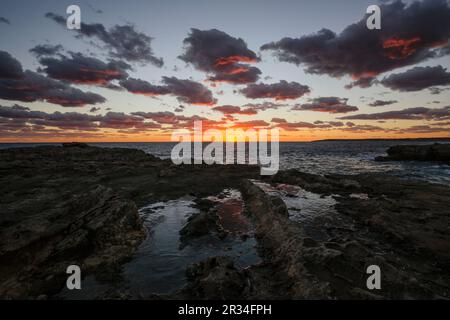 Punta-Plana-Steinbruch, im Hintergrund Fischerhütten und Leuchtfeuer, S'Estalella, Estanyol, llucmajor, mallorca, balearen, spanien, europa. Stockfoto