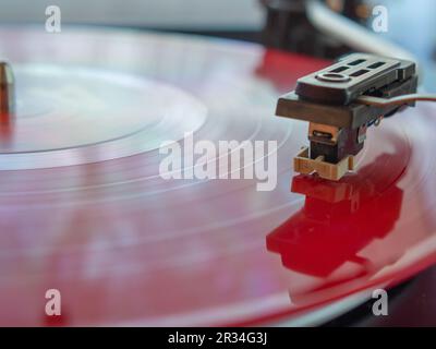 Detail einer Nadel auf einer Spur einer roten Vinylplatte. Klassischer Plattenspieler. Stockfoto